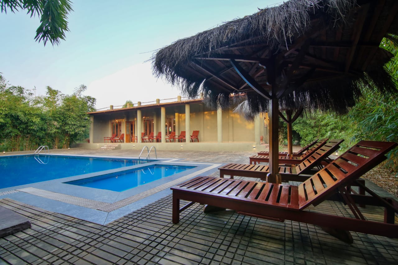 Thatched cabana and teak loungers beside the swimming pool