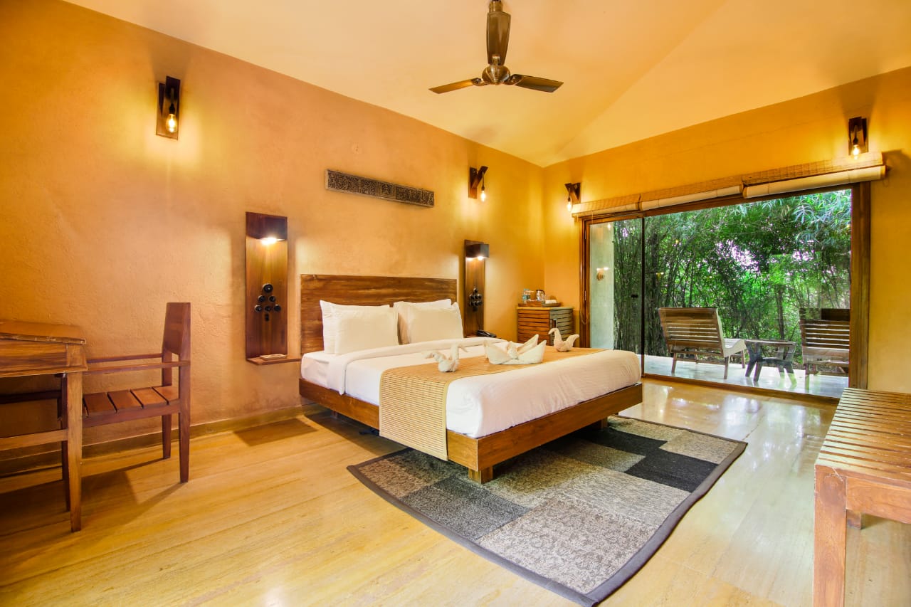Cottage bedroom with glass doors opening onto the green treeline