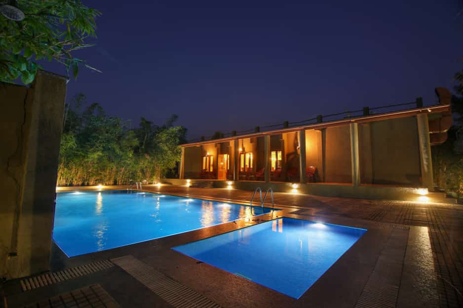 Swimming pool lit blue at night beside the cottages