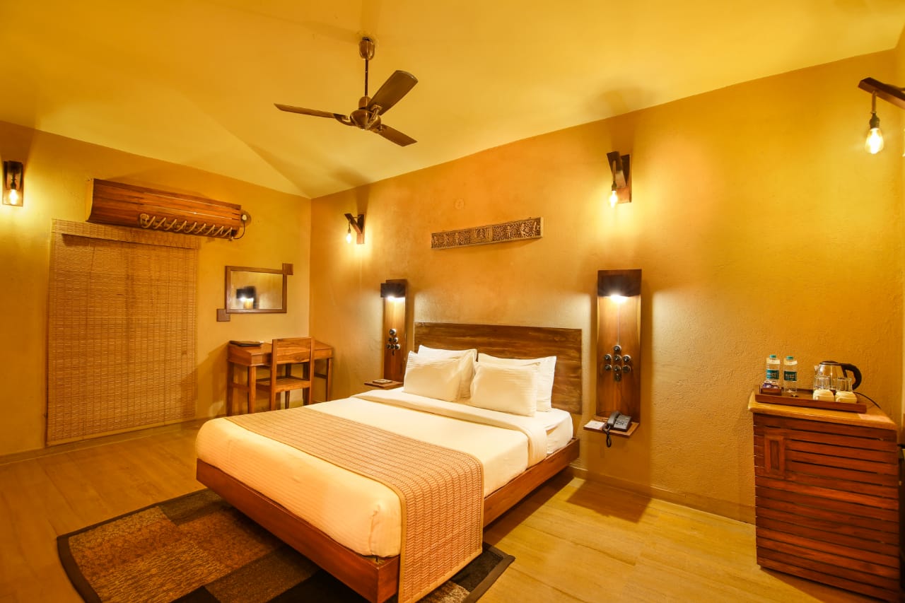 Luxury cottage bedroom with teak furniture, warm sconces and forest light